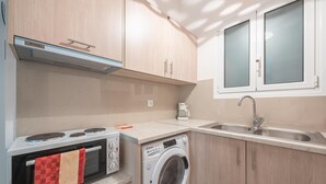 A compact kitchen with a built-in oven, microwave, and a front-loading washing machine. - Cozy Acropolis Studio by Cloudkeys (Athens)