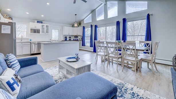 Un salon moderne comprenant un canapé, une table basse et un coin repas avec des chaises.