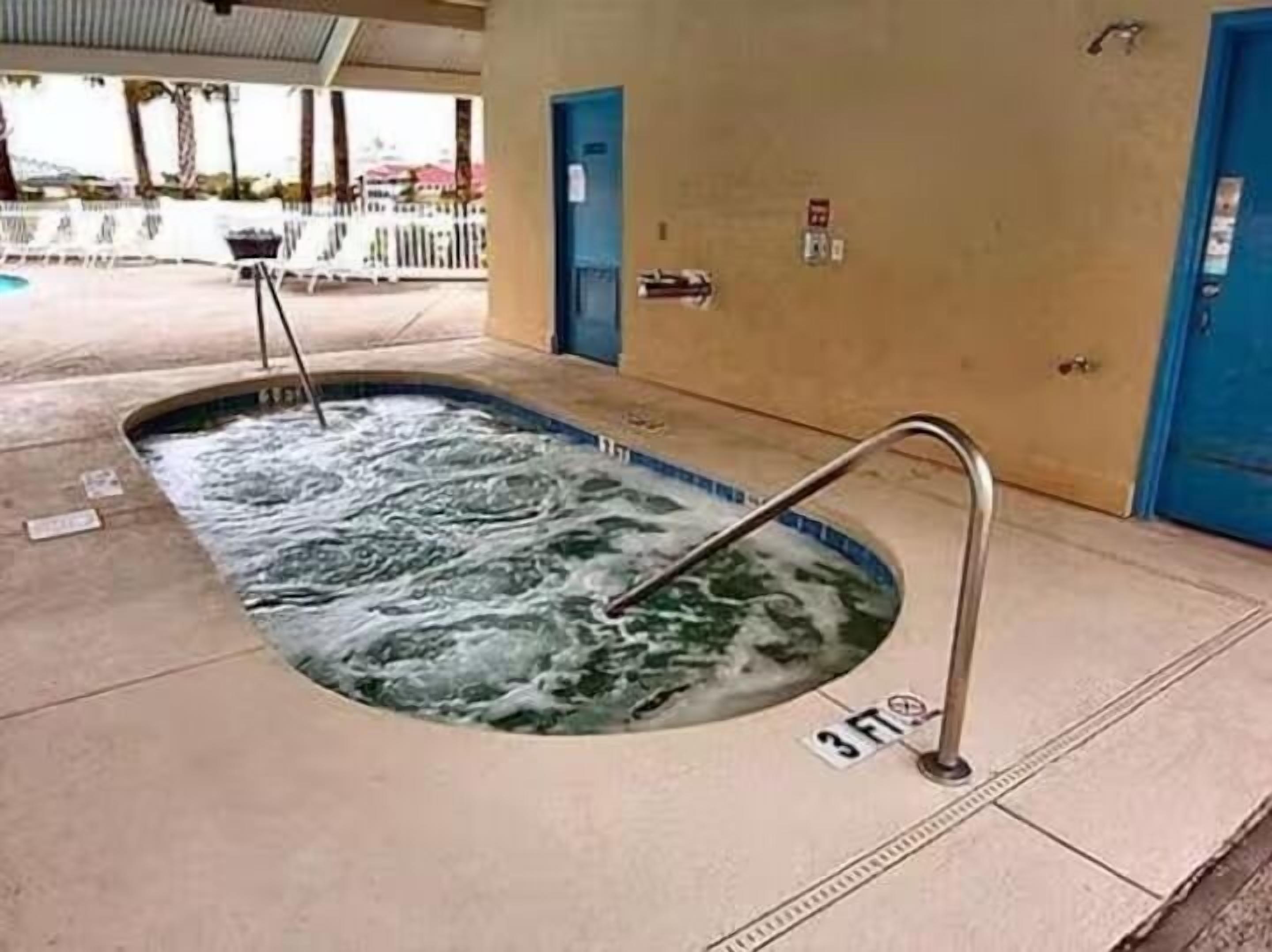 Un bain à remous avec un escalier en métal, une porte bleue et un panneau indiquant « 3 pieds » sur le sol.