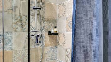 A shower area with patterned tiles and a glass door.