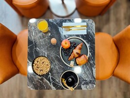 A breakfast tray with croissants, an apple, grapes, a glass of orange juice, a bowl of cereal, and a cup of coffee.