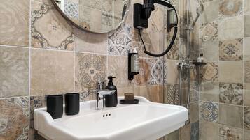 A bathroom with a white sink, black soap dispenser, and a hairdryer mounted on the wall.