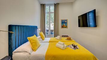 Habitación de hotel con dos camas, televisión y ventana con cortinas.