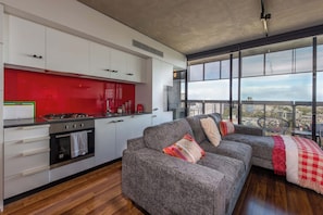 Eine moderne Küche mit weißen Schränken, einer roten Spritzschutzwand und einem großen Fenster mit Blick auf die Stadt.