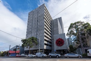 A modern building with a unique facade, multiple parking spaces, and a prominent red sculpture.