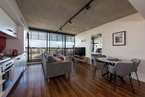 A modern living space with a large window, a dining area, and a kitchen.