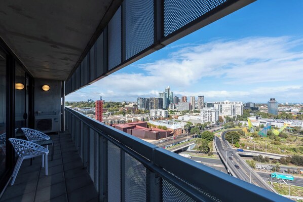 A balcony with a city view, outdoor seating, and a modern building structure.