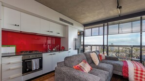 Una cocina moderna con armarios blancos, un salpicadero rojo y un amplio ventanal con vistas a la ciudad.