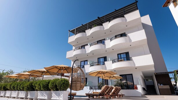 A modern hotel with multiple balconies, outdoor seating, and umbrellas. - Monel Hotel (Ksamil)