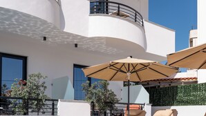 A rooftop swimming pool with lounge chairs and umbrellas, surrounded by a modern building with balconies. - Monel Hotel (Ksamil)