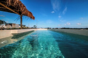 A clear blue pool with a thatched roof structure on one side, surrounded by a low concrete wall. - Villa Emilia Tulum downtown with pool (Tulum)