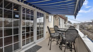 Un patio techado con mesa y sillas, ventanas amplias y vista a la calle.