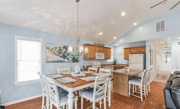 Una cocina amplia con comedor, muebles de madera y una lámpara de araña.