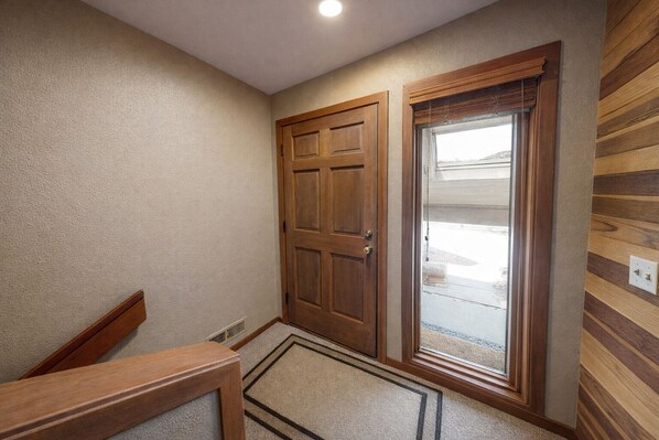 A hallway with a wooden door, a glass door, and a wooden bench.