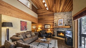 Un salon chaleureux avec une cheminée, un plafond en bois et un mur en pierre.