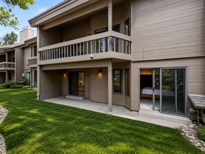 A multi-story residential building with a balcony, large windows, and a well-maintained lawn.