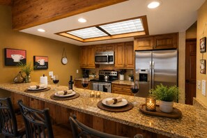 A kitchen with wooden cabinets, a stainless steel refrigerator, a microwave, and a coffee maker. - Deer Valley Adventure Retreat with Free Ski Shuttle 1791 (Park City)