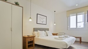 Ein Schlafzimmer mit Bett, Nachttischen, einem Kleiderschrank und einem Fenster.