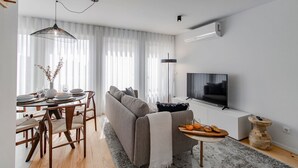 Ett modernt vardagsrum med en soffa, ett matbord och en tv.
