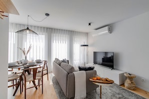 Ein modernes Wohnzimmer mit einer Couch, einem Esstisch und einem Fernseher.