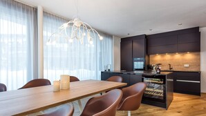 Una cucina moderna con mobili scuri, un piano di lavoro in legno e una cantinetta per vini.