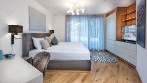 Una camera da letto moderna con un letto, comodini, una TV e un'ampia finestra con tende.
