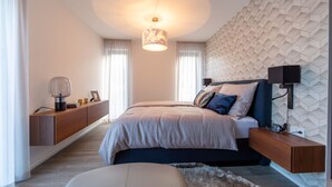 Une chambre moderne avec un lit, des tables de chevet, une lampe et un motif géométrique sur le mur.