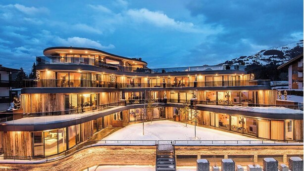 Un hôtel à plusieurs étages, doté d’une façade incurvée, de grandes fenêtres en verre et d’un sol recouvert de neige.