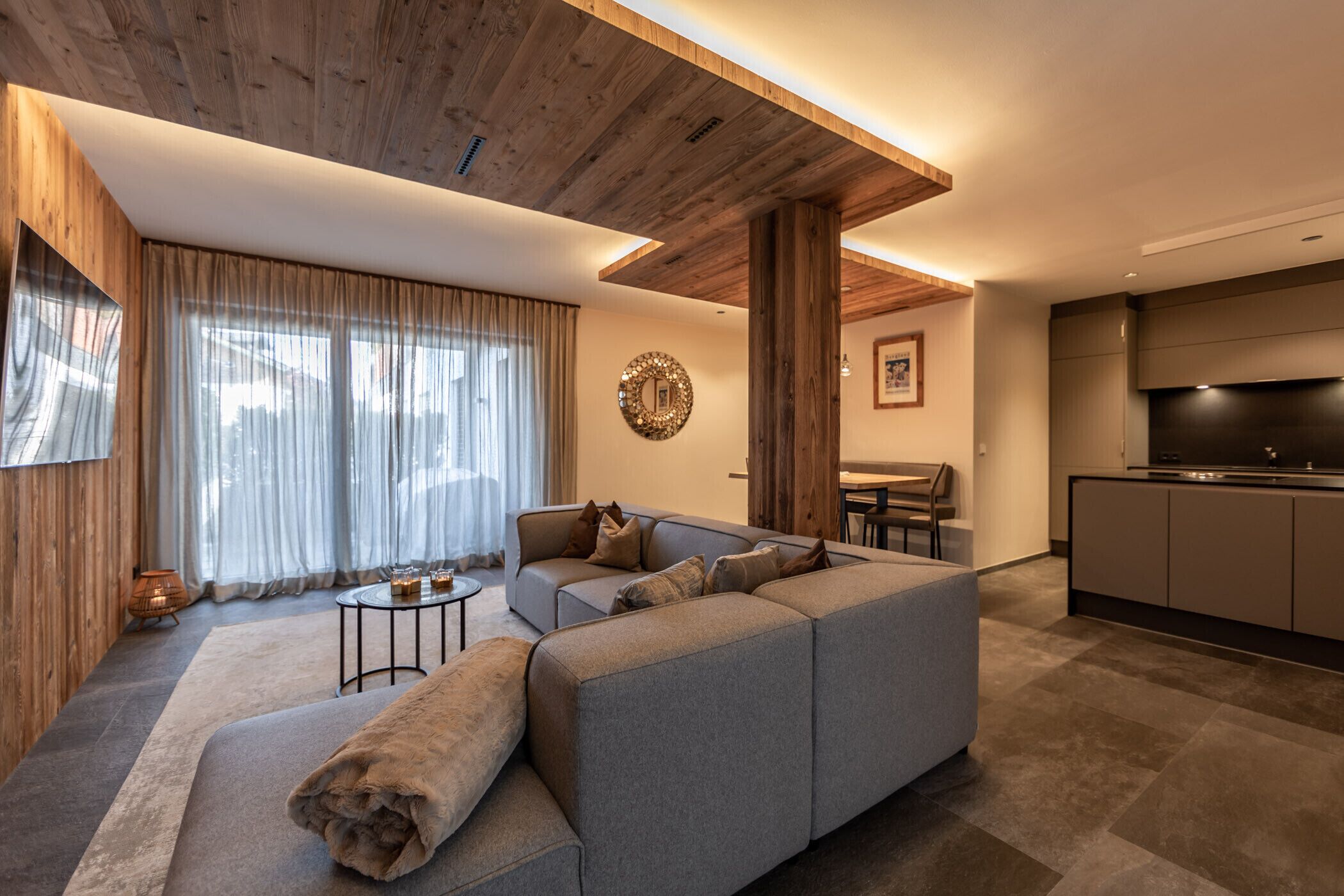 A modern living room with a sectional sofa, a coffee table, and a dining area with a table and chairs.