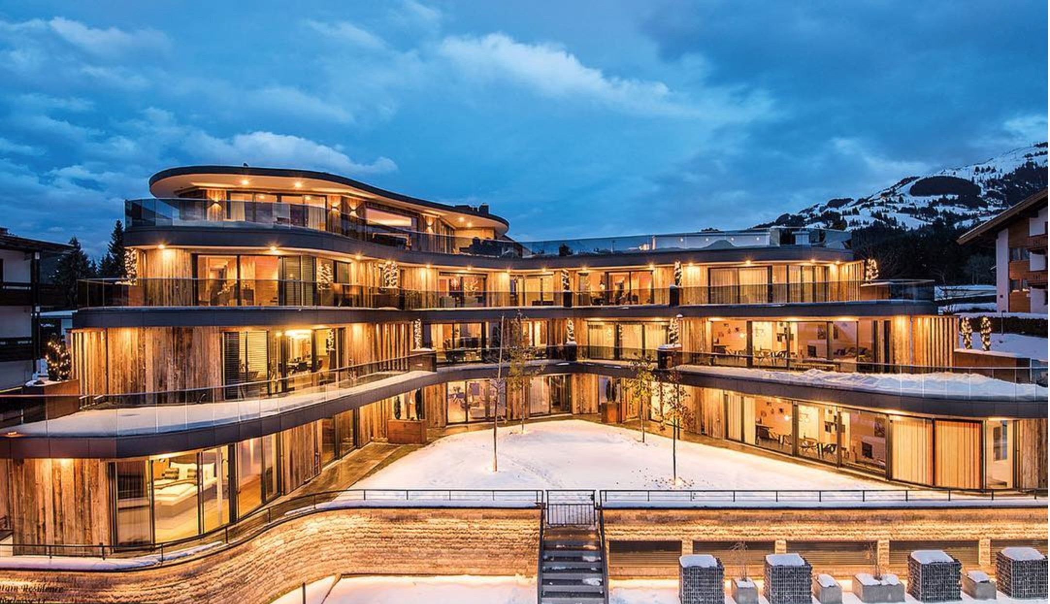 Un hôtel à plusieurs étages, doté d’une façade incurvée, de grandes fenêtres en verre et d’un sol recouvert de neige.