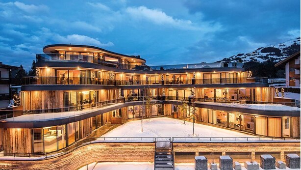 A multi-story hotel with a curved facade, large glass windows, and a snow-covered ground.