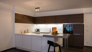 A modern kitchen with dark cabinets, a stainless steel refrigerator, and a bar stool.