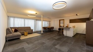 A modern living room with a sofa, dining table, and kitchen area.