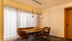 A dining area with a wooden table, four chairs, and pendant lights.