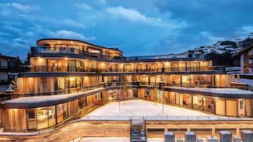 A multi-story hotel with a curved facade, large glass windows, and a snow-covered ground.
