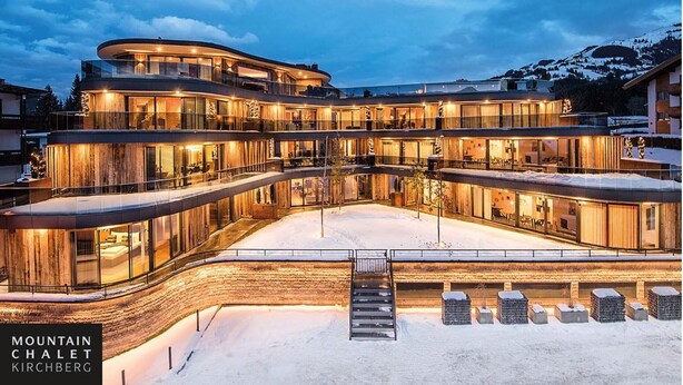 A multi-story hotel with a curved facade, large glass windows, and a snow-covered ground. - Chalet Alpin Jewel T7 (Kirchberg in Tirol)