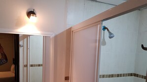Eenvoudige tweepersoonskamer | Badkamer | Een douche, een regendouche, handdoeken, zeep