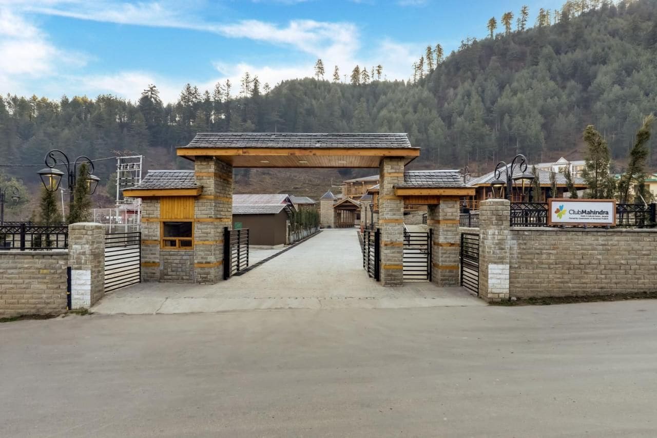 Un cancello con arco in legno che conduce a un edificio con facciata in pietra.