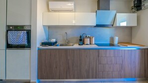 Una cocina moderna con horno empotrado, un lavamanos y una encimera con diversos electrodomésticos.