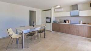 Una cocina moderna con comedor, que cuenta con una isla grande, electrodomésticos integrados y un diseño limpio y minimalista.