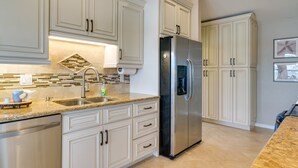 A modern kitchen with white cabinetry, stainless steel appliances, and a granite countertop. - Waterfront Cape Coral Home w/ Pool & Gulf Access (Cape Coral)