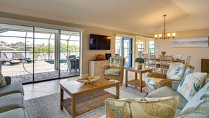 A spacious living room with a large sliding glass door leading to a patio area. - Waterfront Cape Coral Home w/ Pool & Gulf Access (Cape Coral)