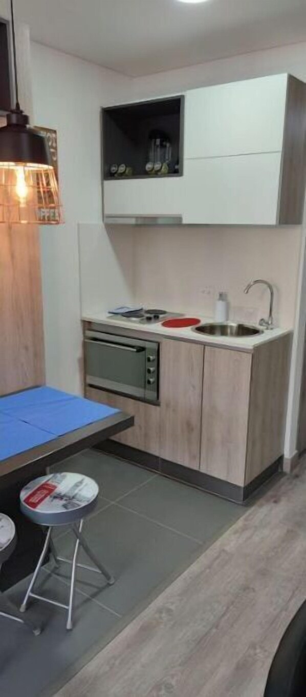Une cuisine compacte dotée d’un four encastré, d’un évier et d’un petit coin repas avec une table et des tabourets.