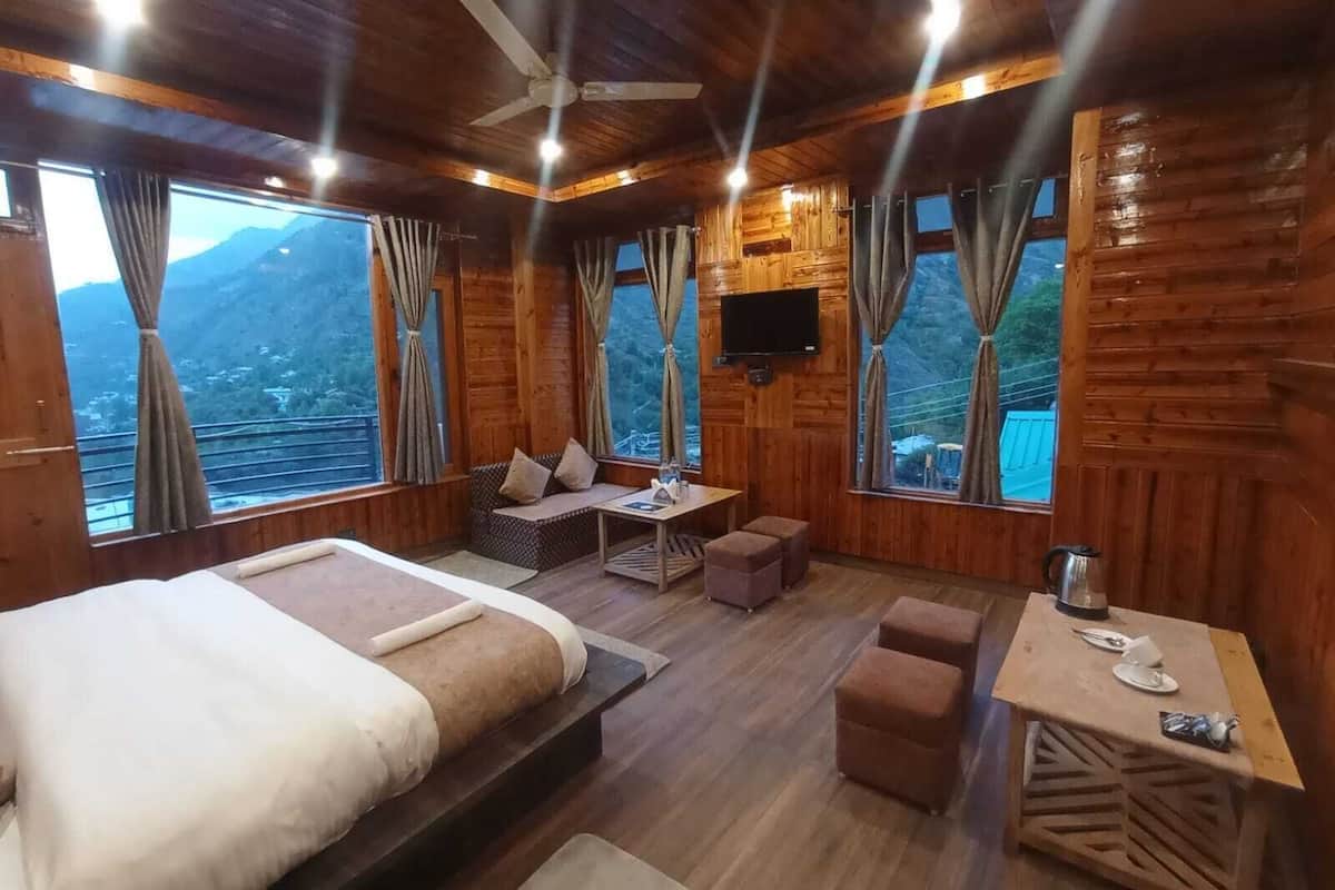 Een houten kamer met een bed, zithoek en een tafel met waterkoker.