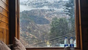 A cozy cabin room with a large window offering a view of a mountainous landscape. - The Black Morel Hotel & Restaurant (Banjar)