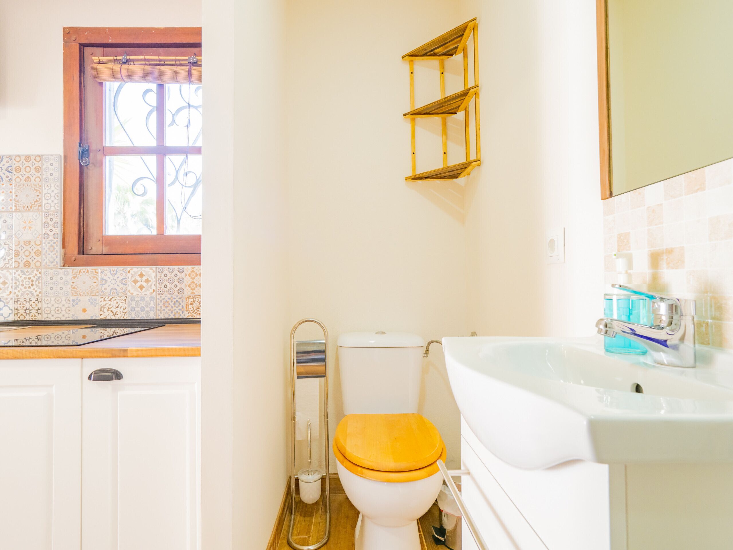 A bathroom with a toilet, sink, and a window with a metal grill.