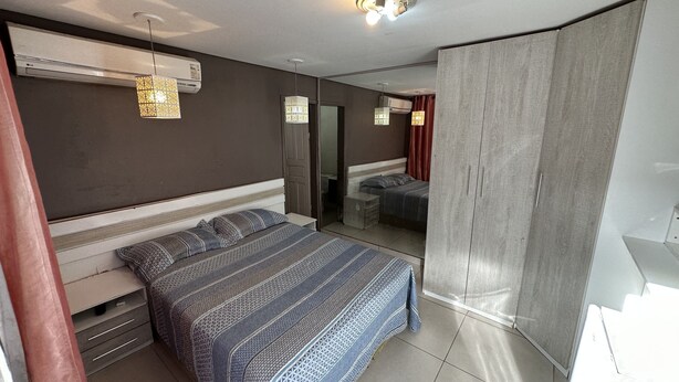 A bedroom with a bed, bedside tables, a wardrobe, and a mirror. - Pousada Residencial - Atrás Shopping pvh (Porto Velho)