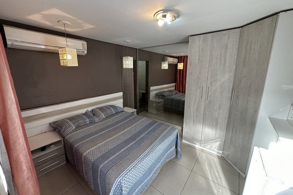 A bedroom with a bed, bedside tables, a wardrobe, and a mirror.