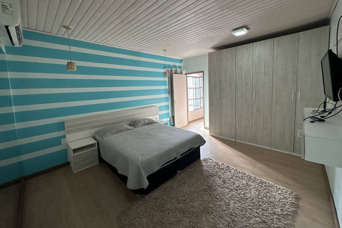 A bedroom with a bed, a wardrobe, a television, and a window.