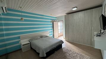 Un dormitorio con una cama, un armario, un televisor y una ventana.